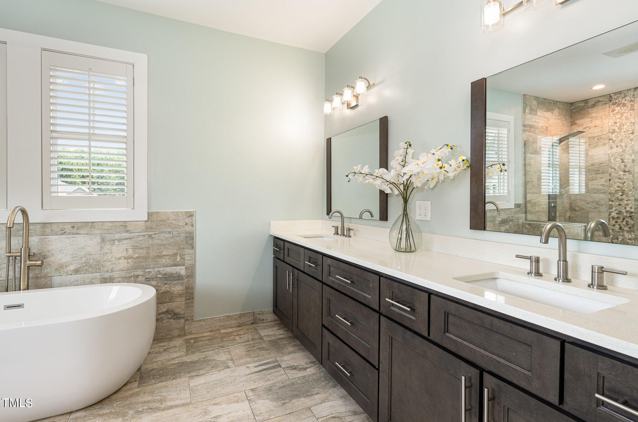 a bathroom with a tub double sink and mirror