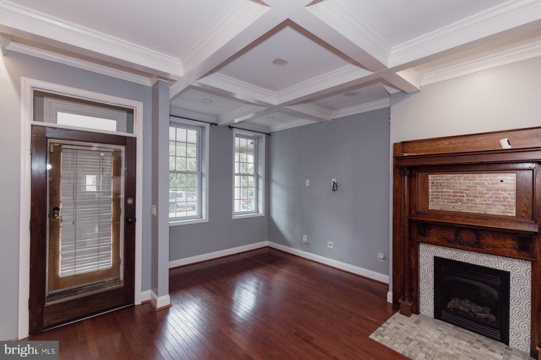 a view of an empty room with wooden floor fireplace and a window