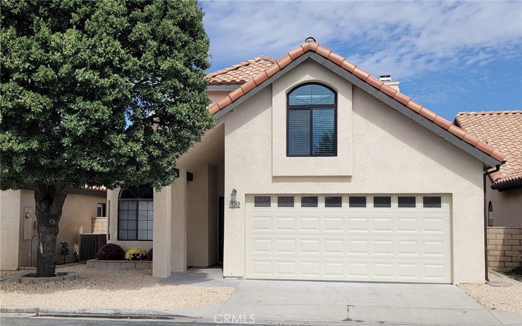 a front view of a house with a tree