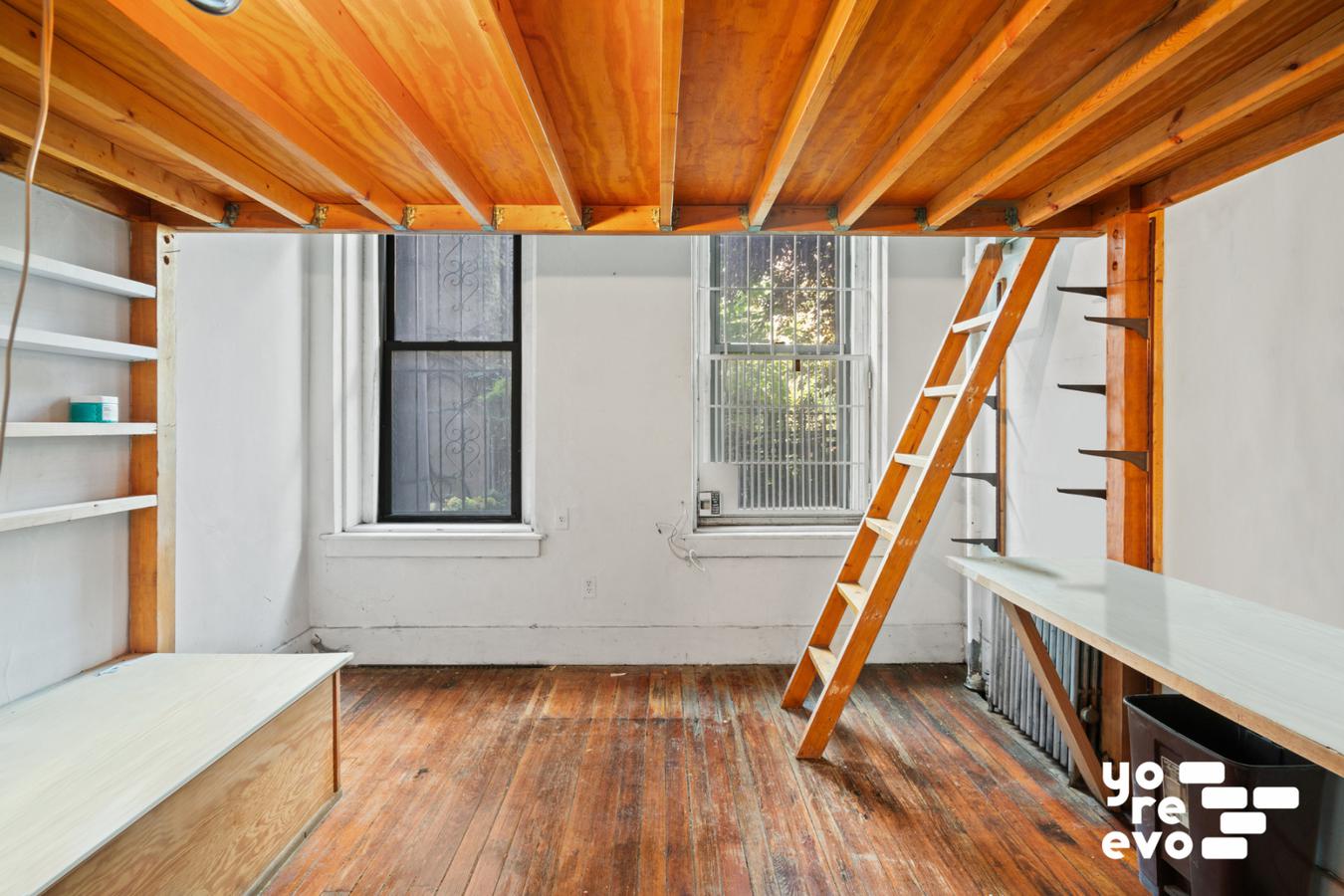 a view of an empty room with wooden floor and stairs