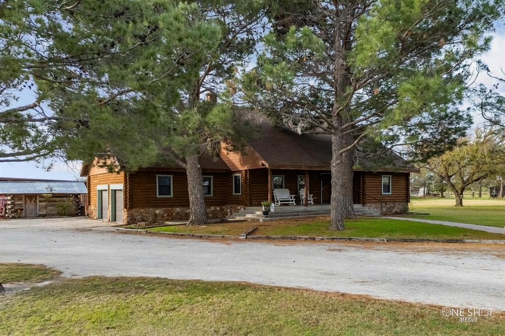 Log home featuring a front lawn, a porch, and a garage