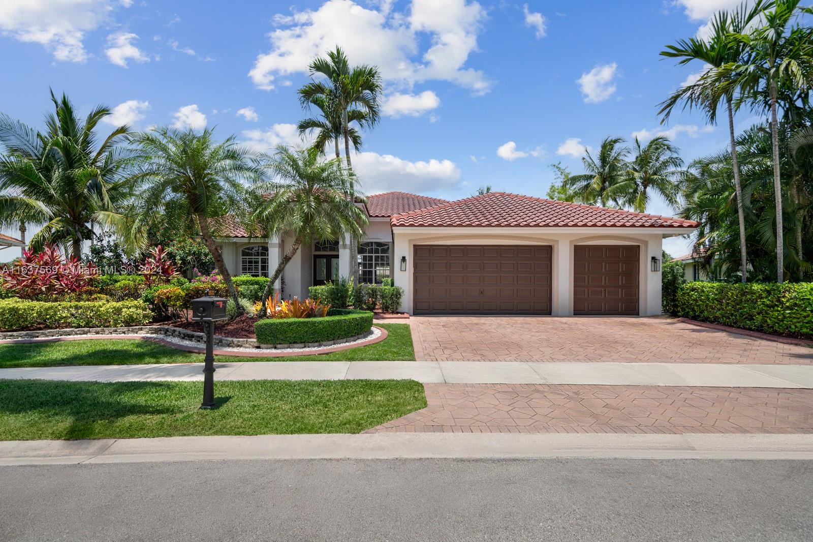 a front view of a house with a yard and palm trees