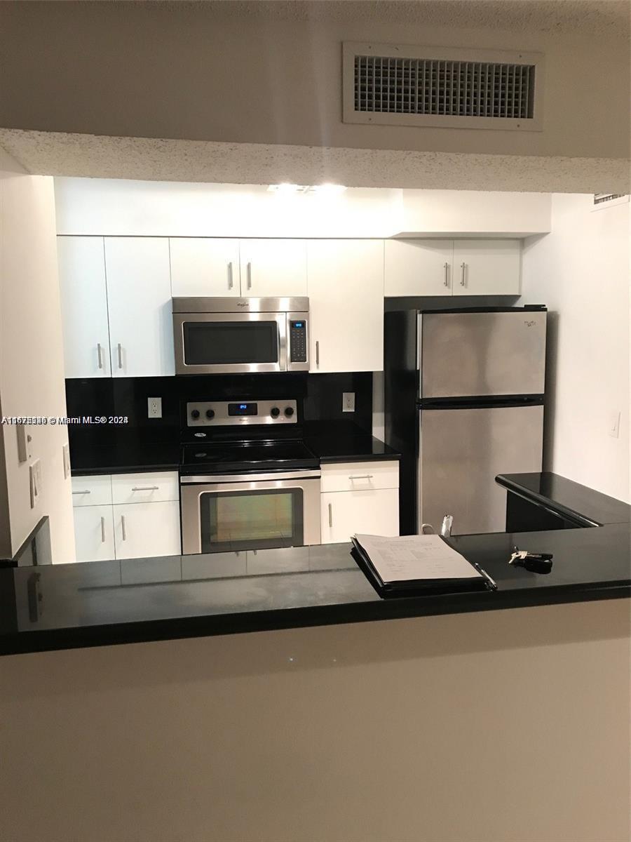 a kitchen with a refrigerator a stove and white cabinets