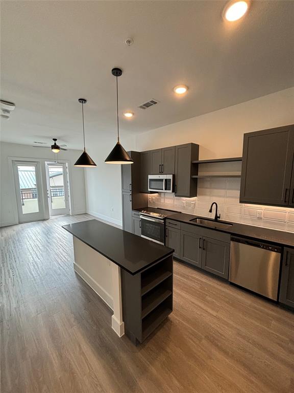 a kitchen with stainless steel appliances granite countertop a sink a stove and wooden floors