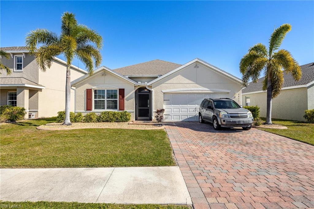 Ranch-style house featuring a garage and a front lawn