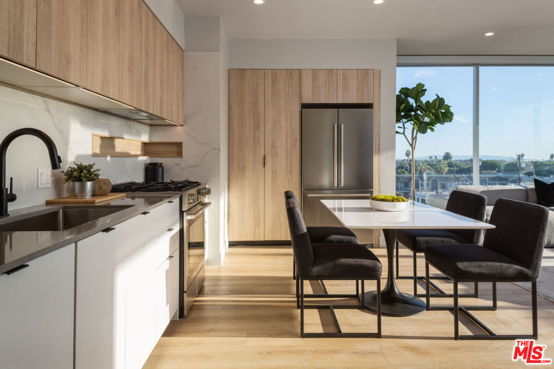 a kitchen with stainless steel appliances granite countertop a table chairs and a refrigerator