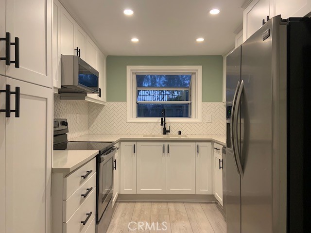 a kitchen with stainless steel appliances a refrigerator sink and white cabinets