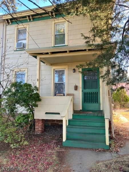 a view of a house with a yard plants and large tree