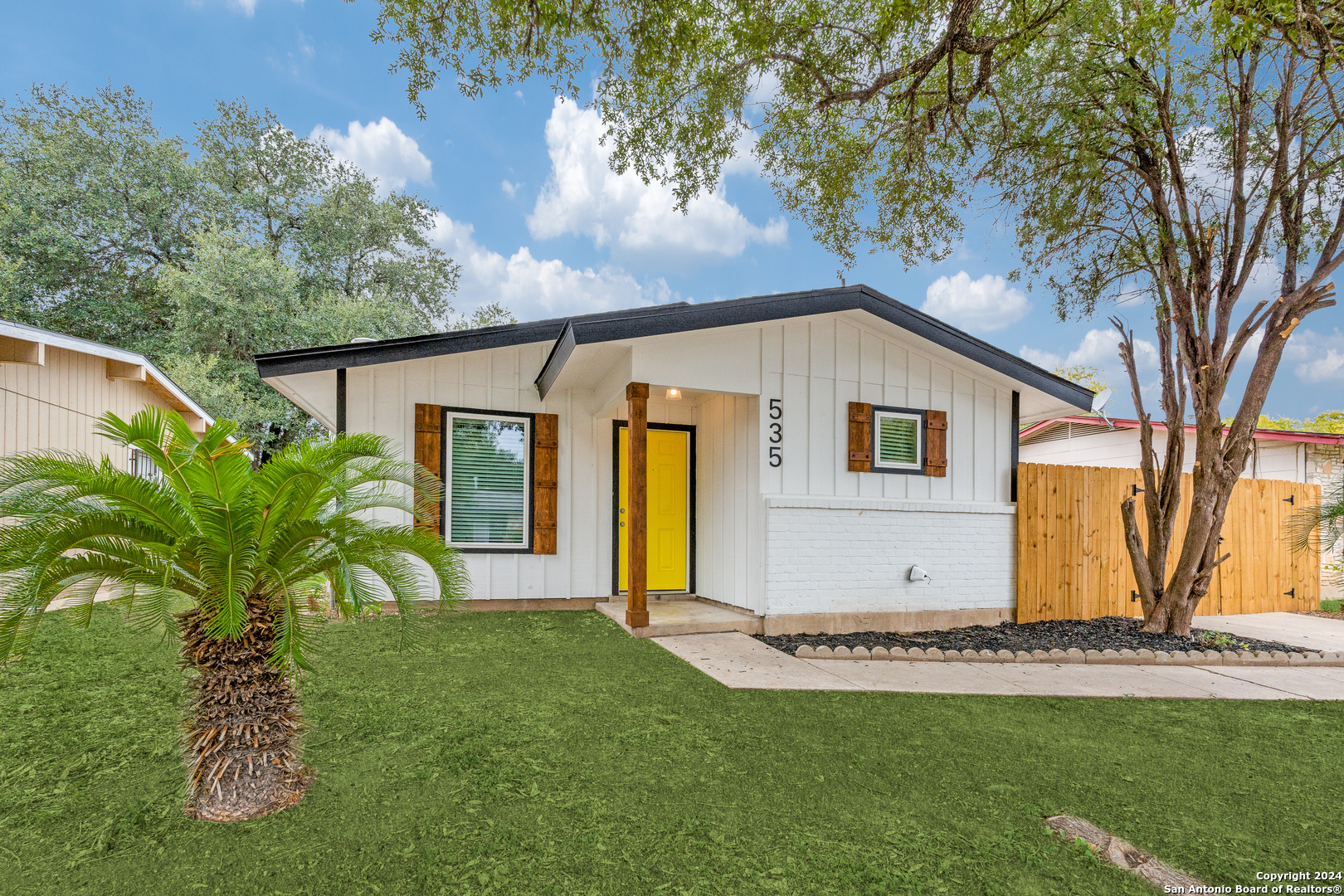 a view of a house with backyard and a tree