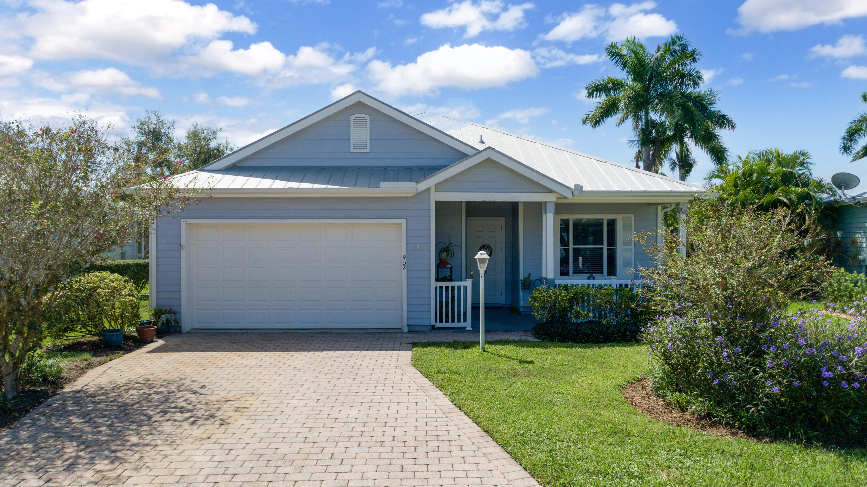 a front view of a house with a yard and potted plants