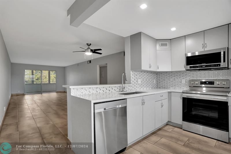 a kitchen with kitchen island granite countertop a stove sink and microwave