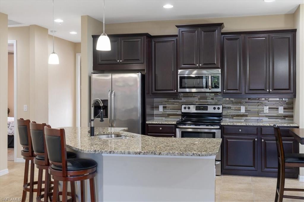 a kitchen with kitchen island granite countertop wooden cabinets and a refrigerator