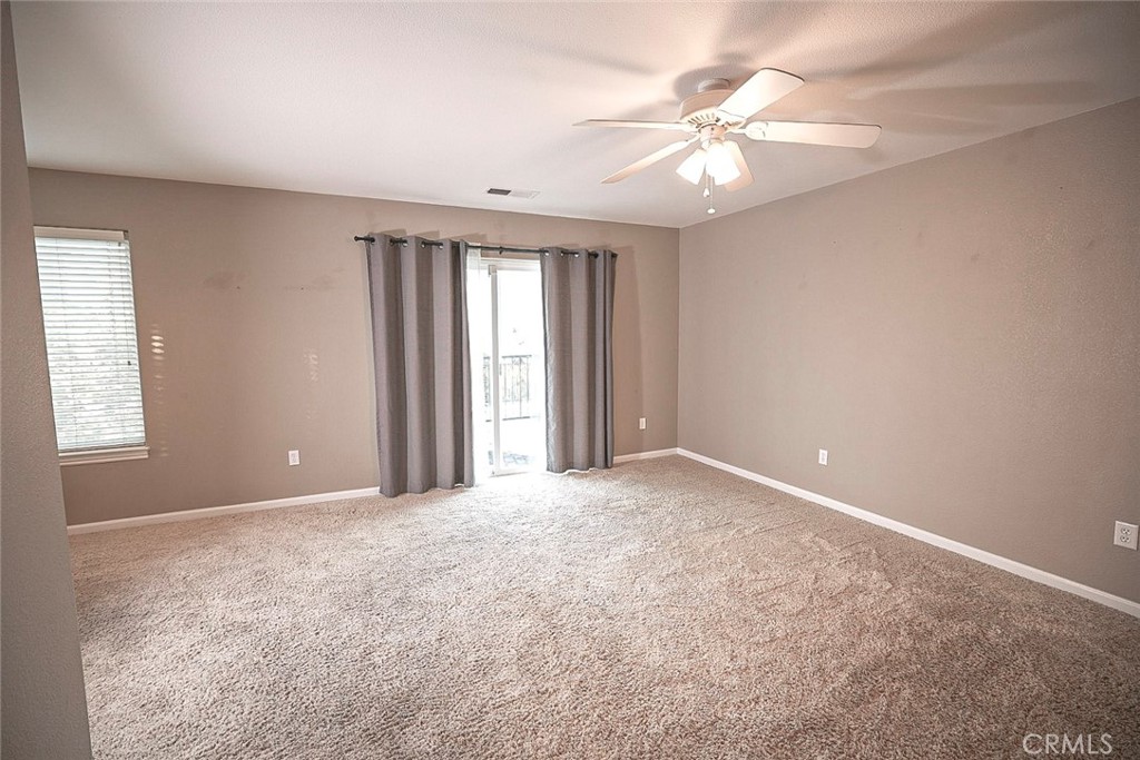 an empty room with windows and chandelier fan