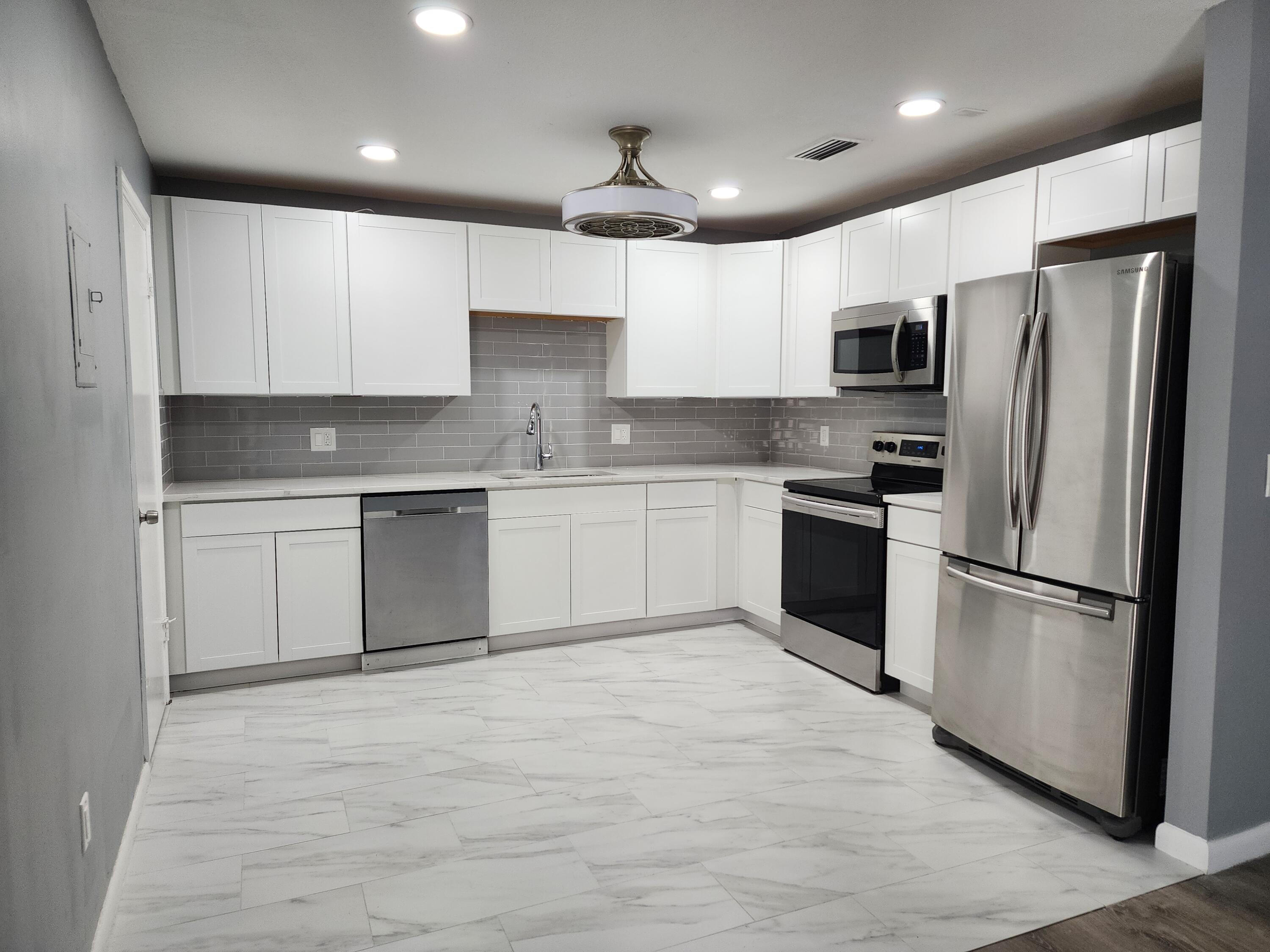 a kitchen with white cabinets stainless steel appliances and a refrigerator