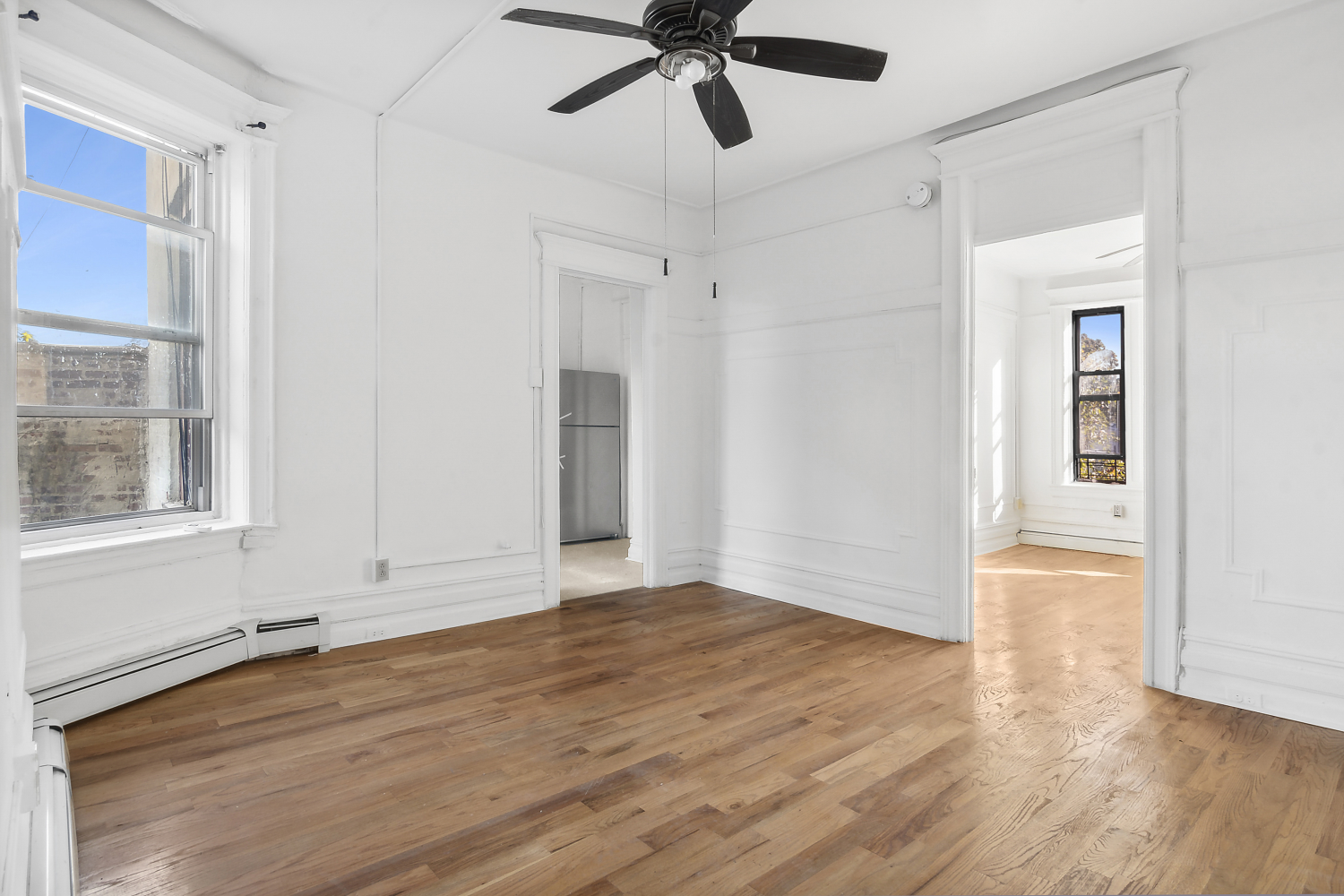 a view of an empty room with wooden floor and a window