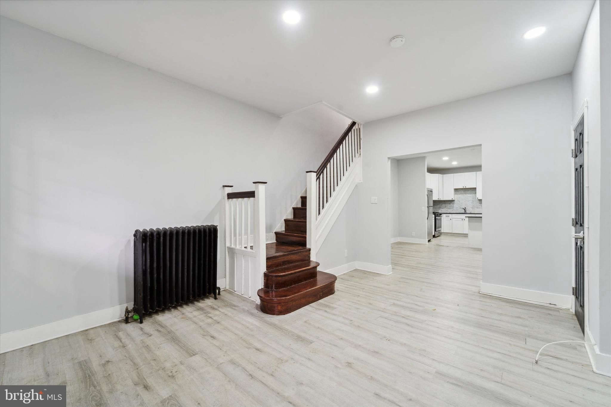 a view of an empty room with wooden floor and stairs