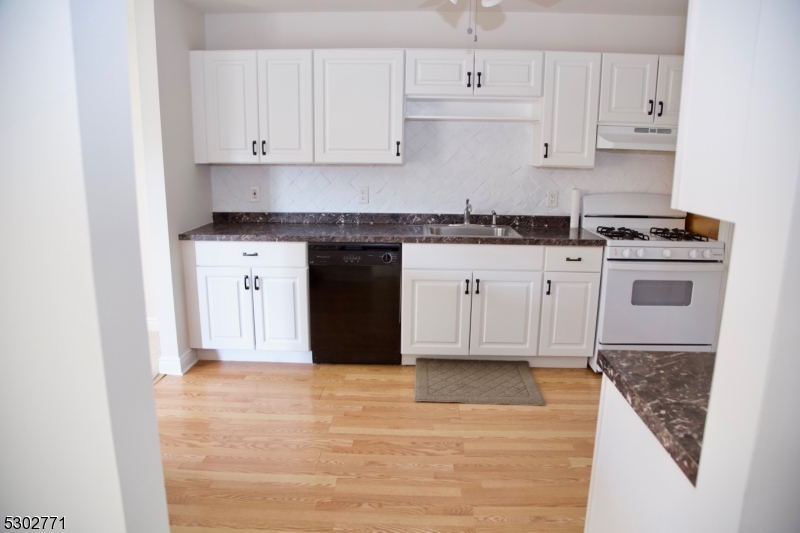 a kitchen with stainless steel appliances granite countertop a stove a sink and white cabinets