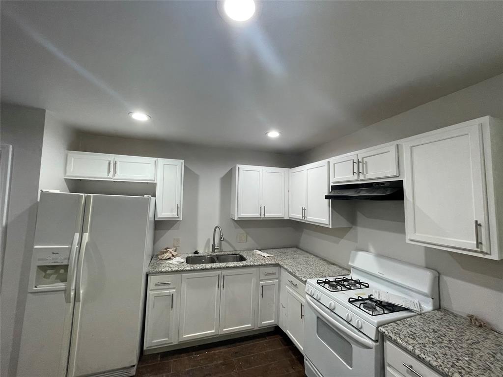 a kitchen with stainless steel appliances a refrigerator a sink and white cabinets