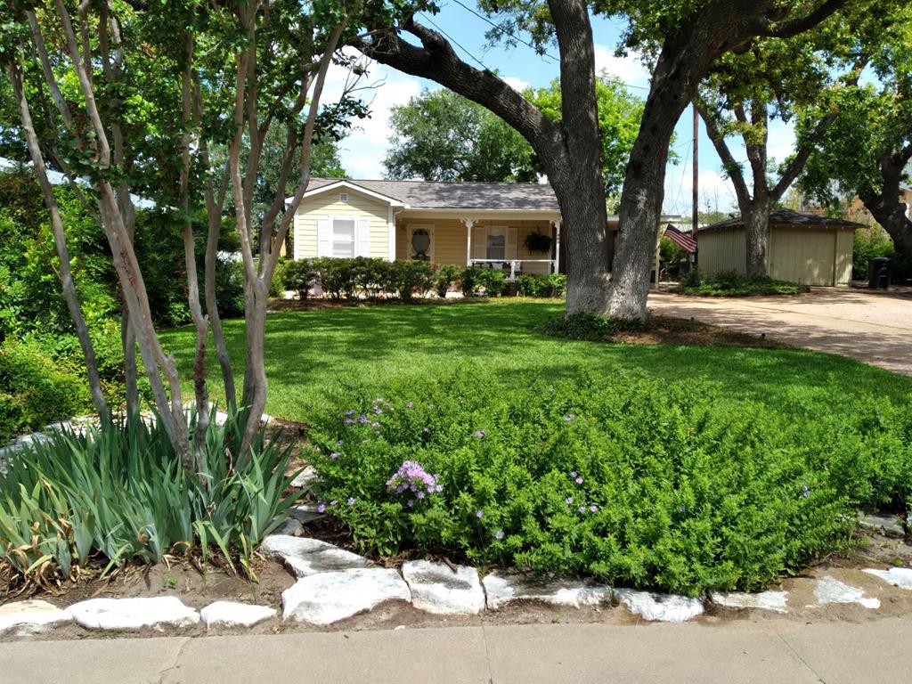 a front view of a house with a yard and a garden