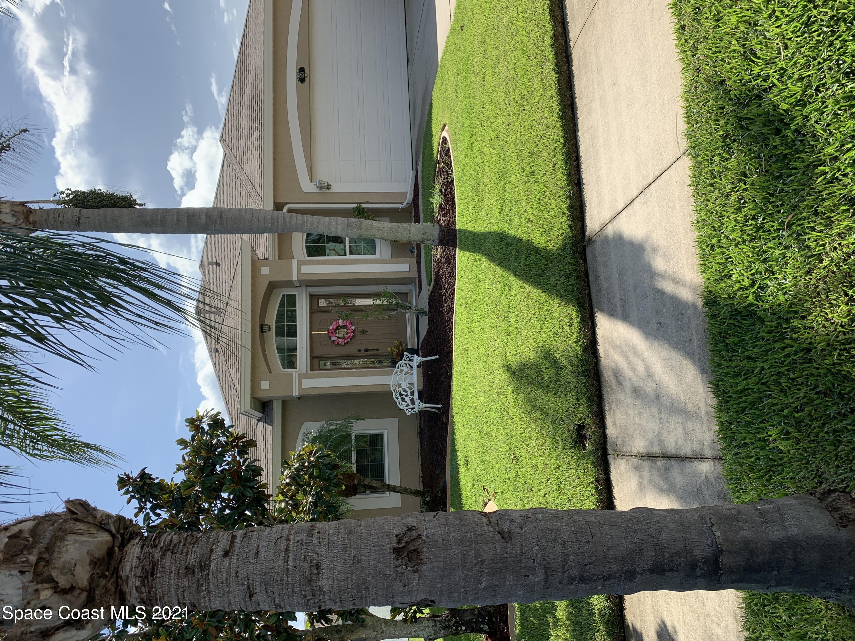 a view of a white house with a big yard and potted plants