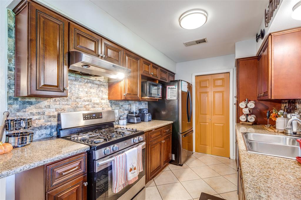 a kitchen with stainless steel appliances granite countertop a stove a sink and a refrigerator