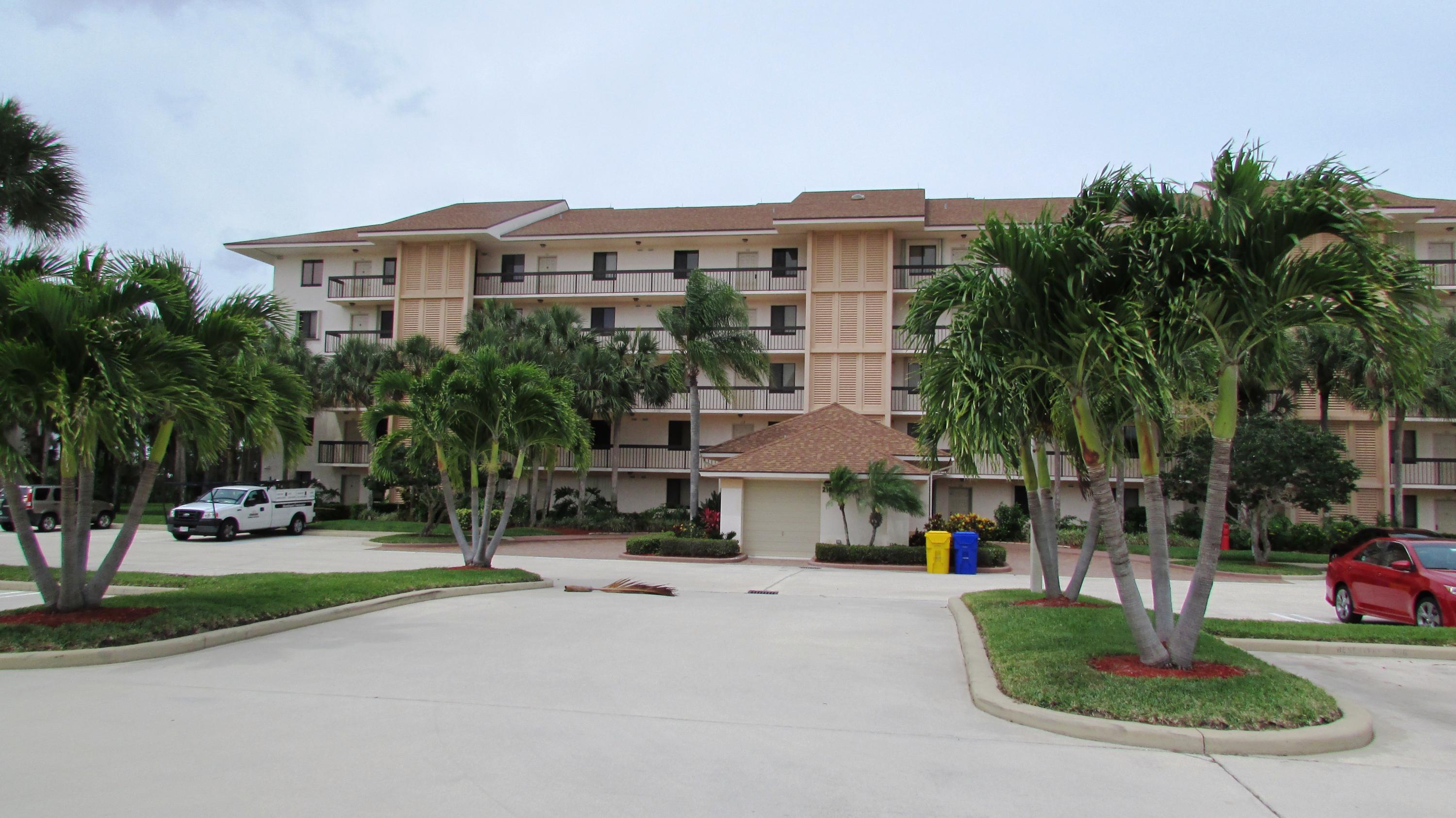 a front view of a building with garden and trees