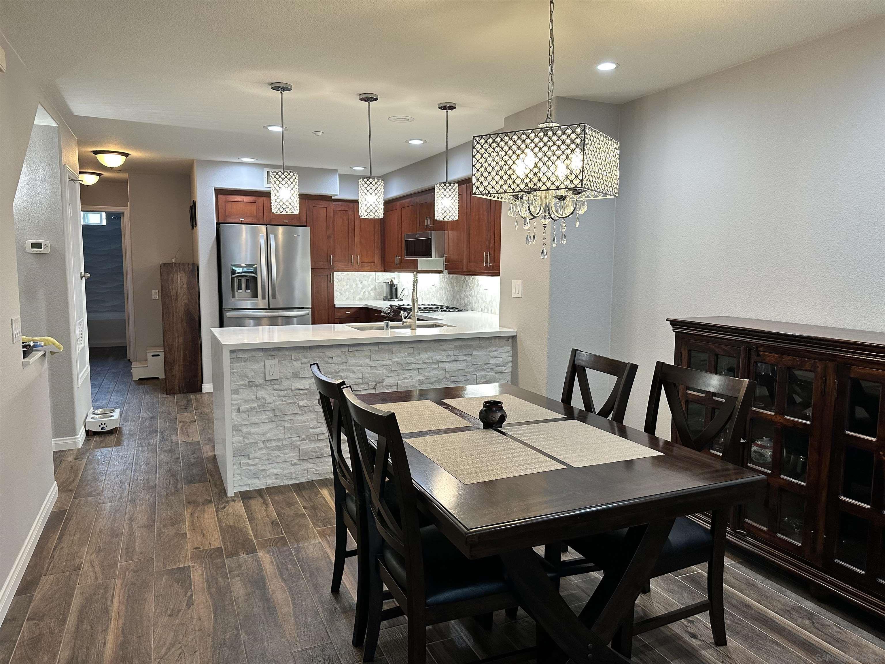 a view of a dining room and livingroom with furniture wooden floor a chandelier