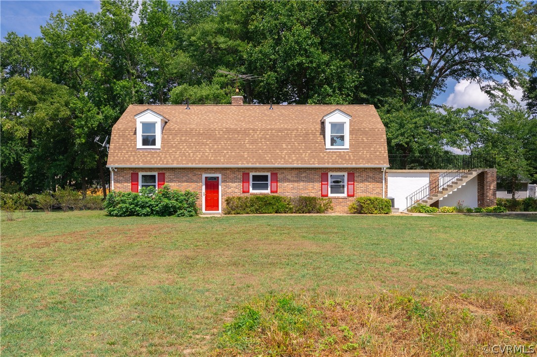 a front view of house with yard and trees in the background