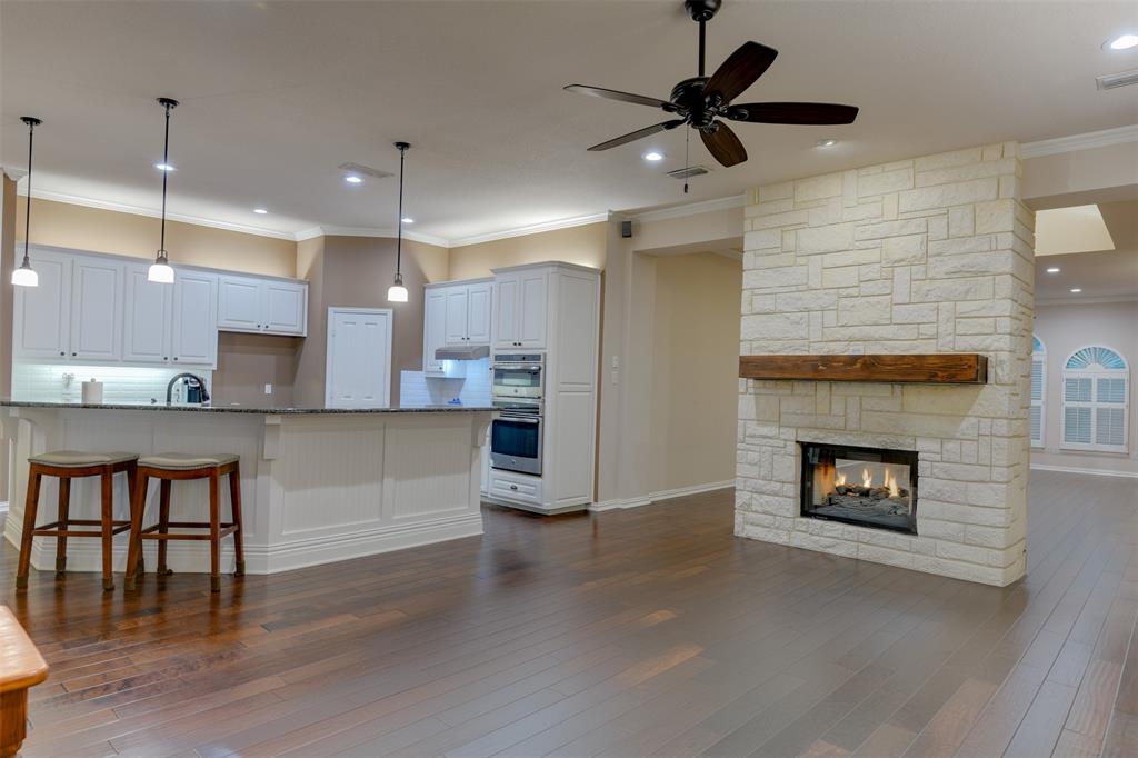 a living room with stainless steel appliances kitchen island a fireplace and a ceiling fan