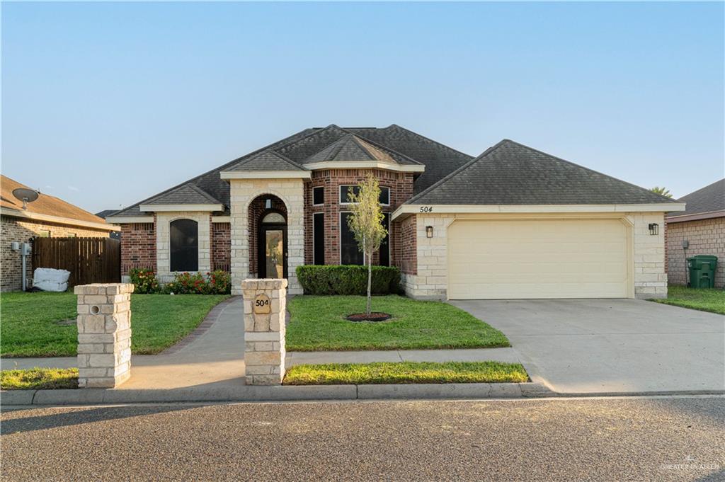 View of front facade featuring a front yard and a garage