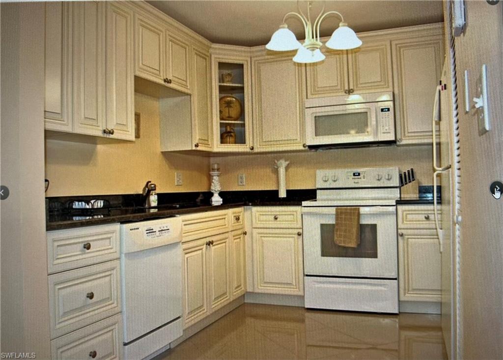 Kitchen featuring cream cabinetry, white appliances, and a chandelier