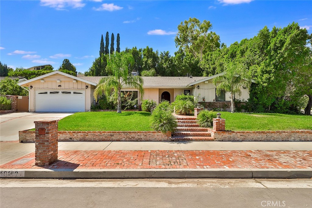 a front view of a house with a yard and potted plants