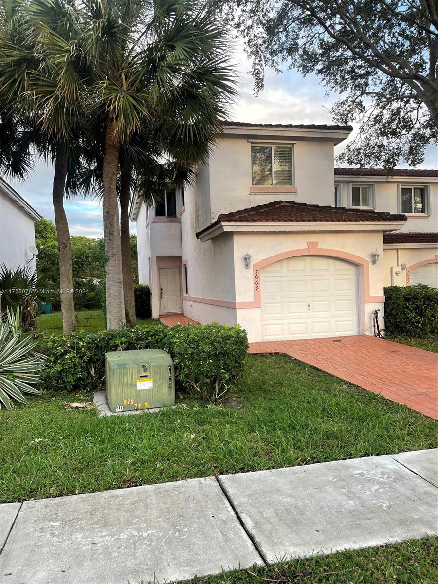 a front view of a house with a garden and palm trees