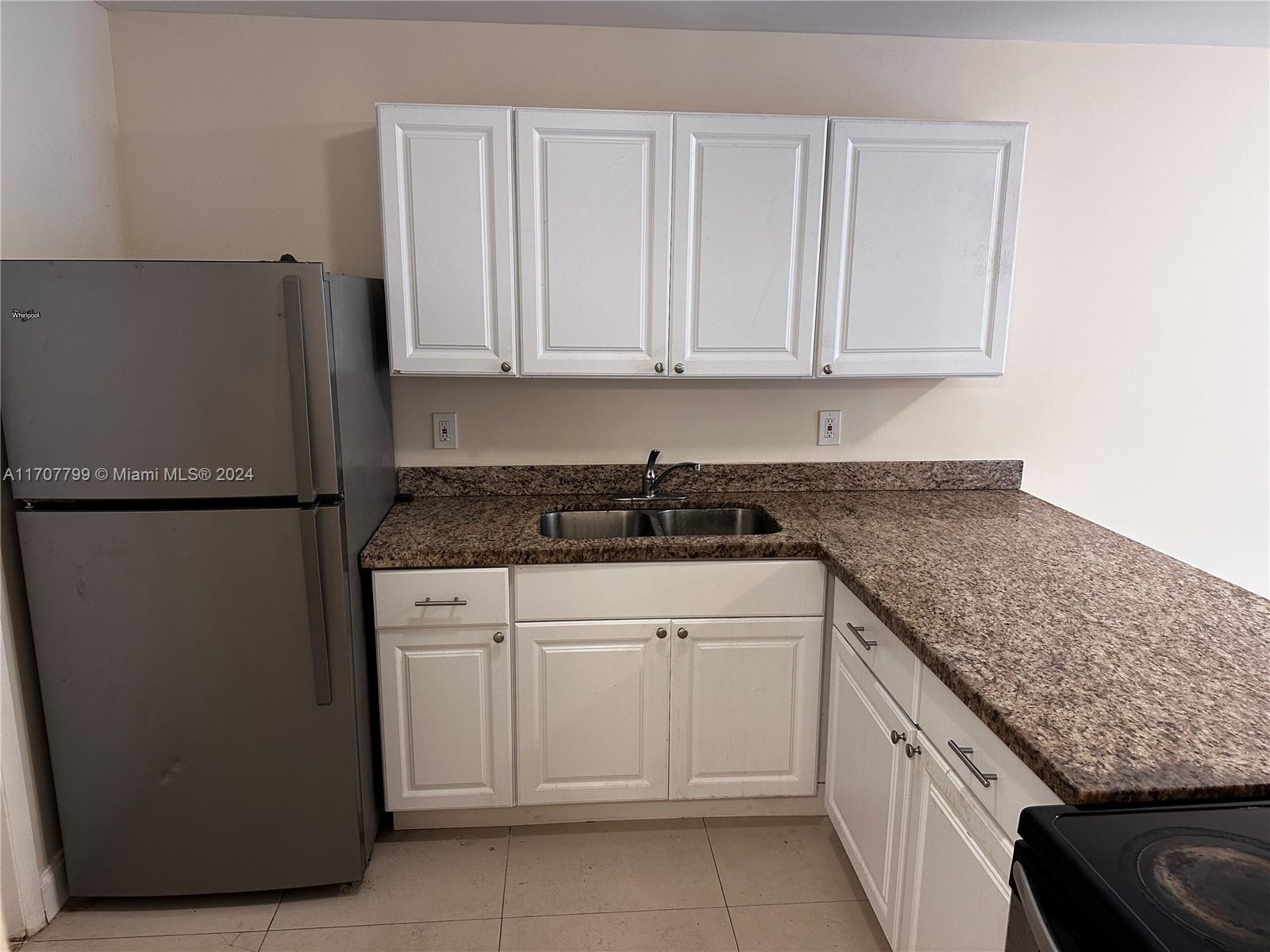 a kitchen with granite countertop white cabinets and stainless steel appliances