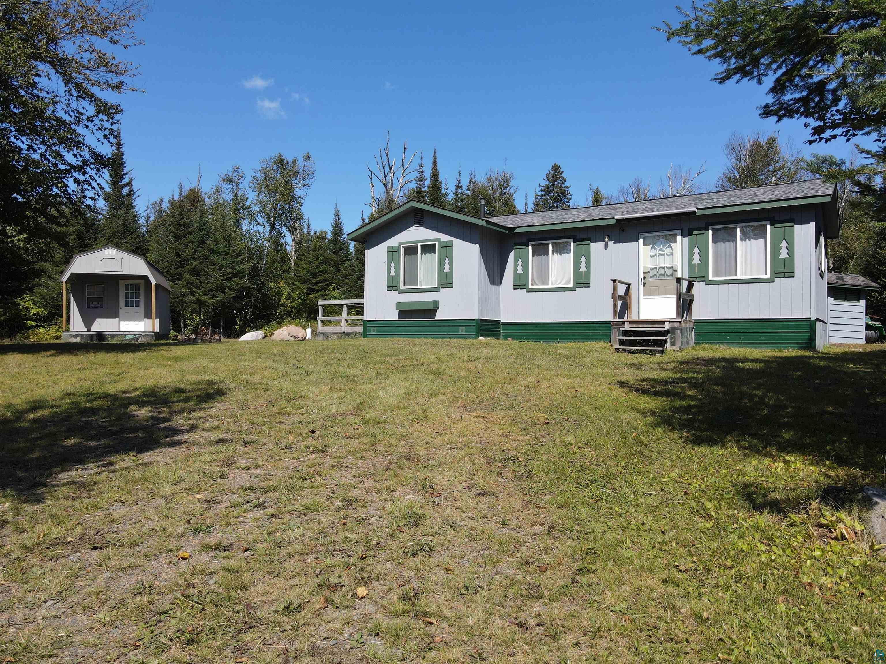 View of front of home featuring a storage shed and a front lawn