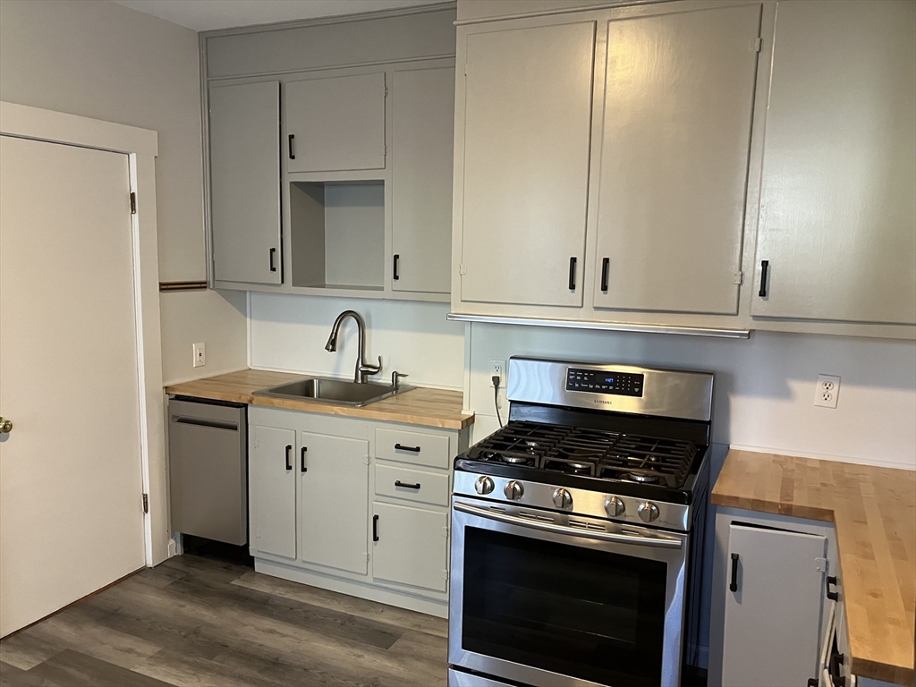 a kitchen with granite countertop white cabinets and stainless steel appliances