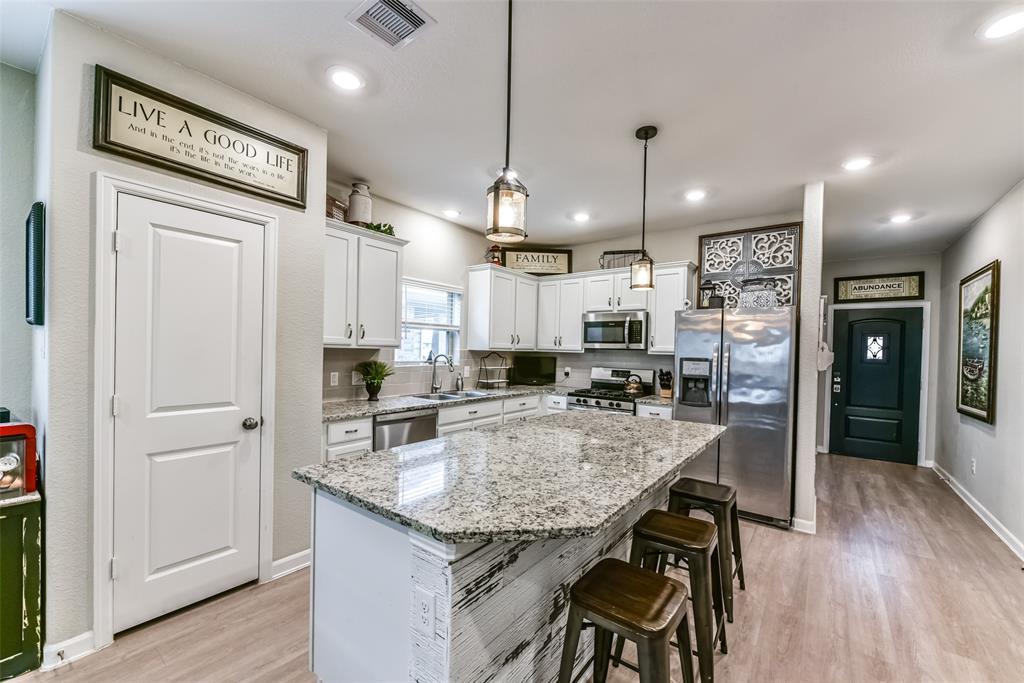 a kitchen with stainless steel appliances granite countertop furniture wooden floor and a refrigerator