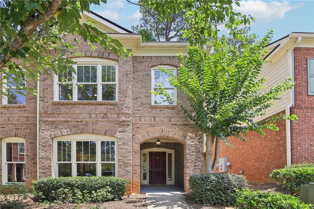 front view of a brick house with a large window and potted plants