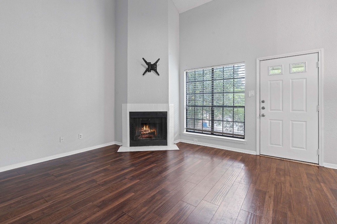 an empty room with wooden floor fireplace and windows