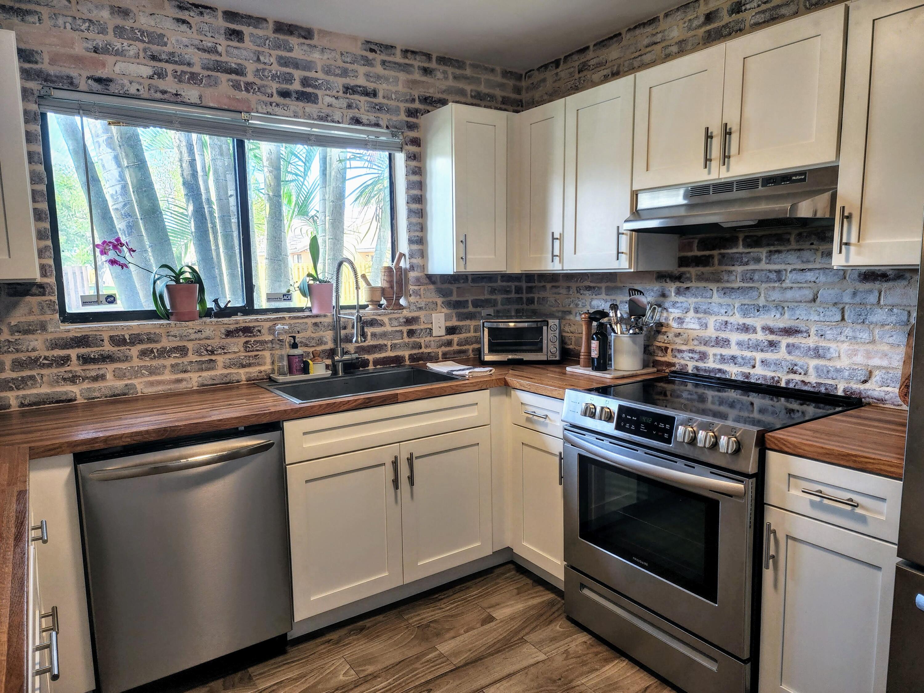 a kitchen with stainless steel appliances white cabinets granite counter tops and a wooden floors