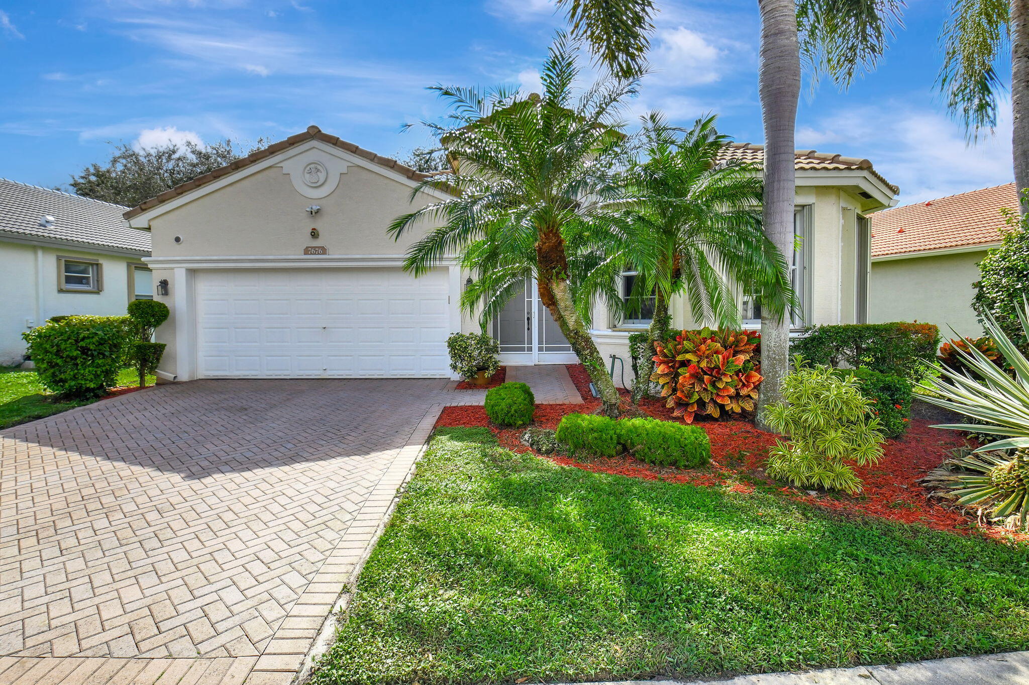 a front view of a house with a yard and potted plants