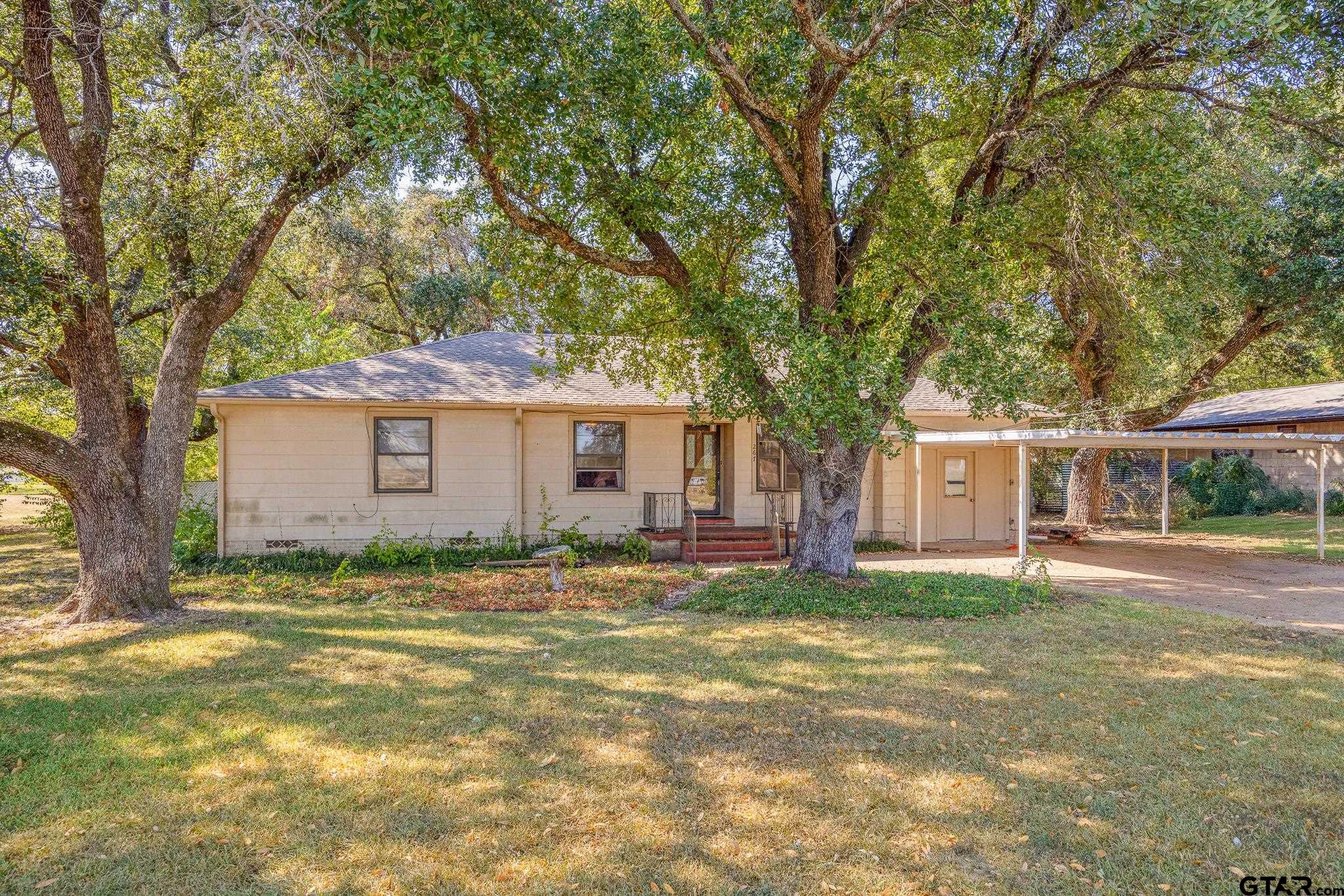 a view of a yard in front of a house with large trees