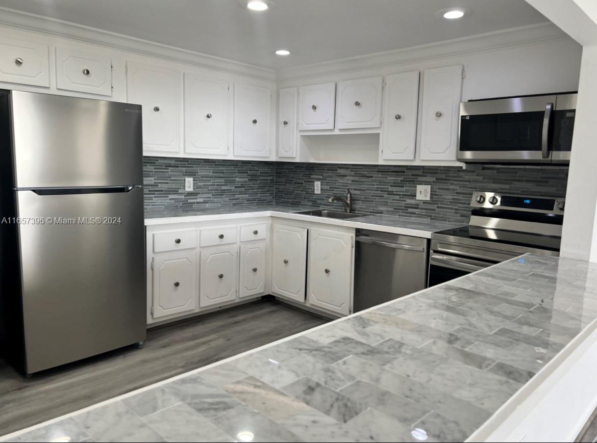 a kitchen with granite countertop white cabinets and stainless steel appliances