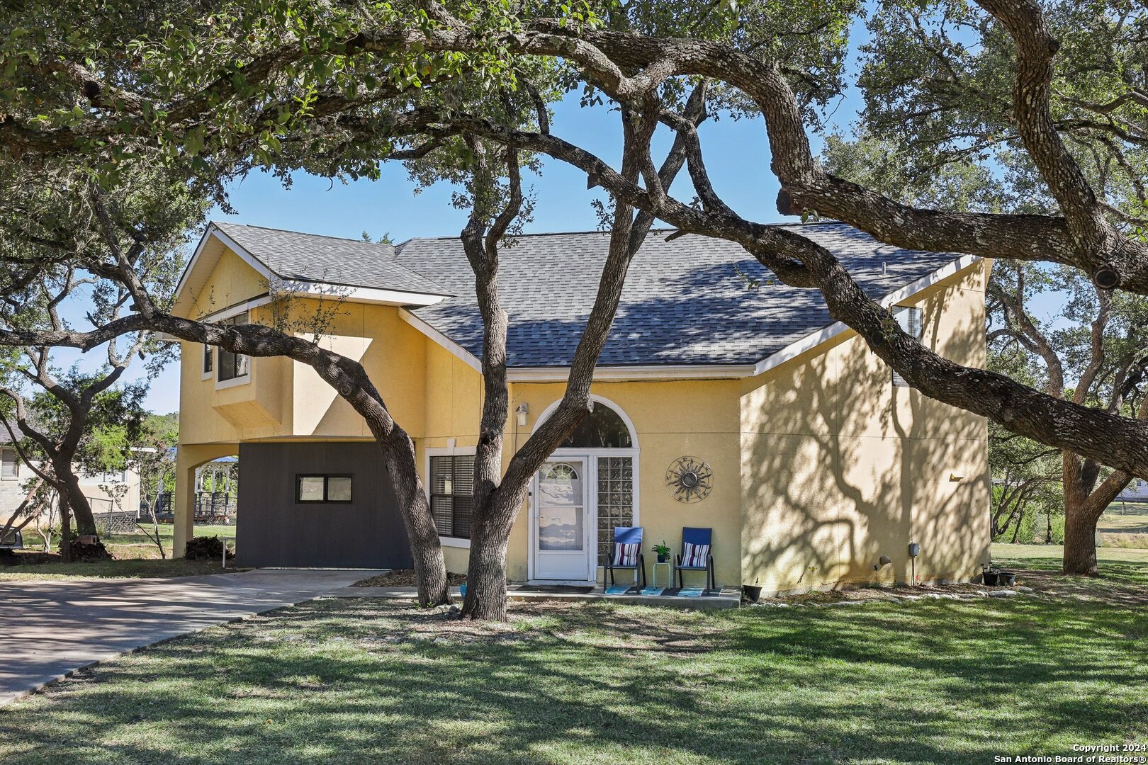 a view of a yard in front of a house with large trees