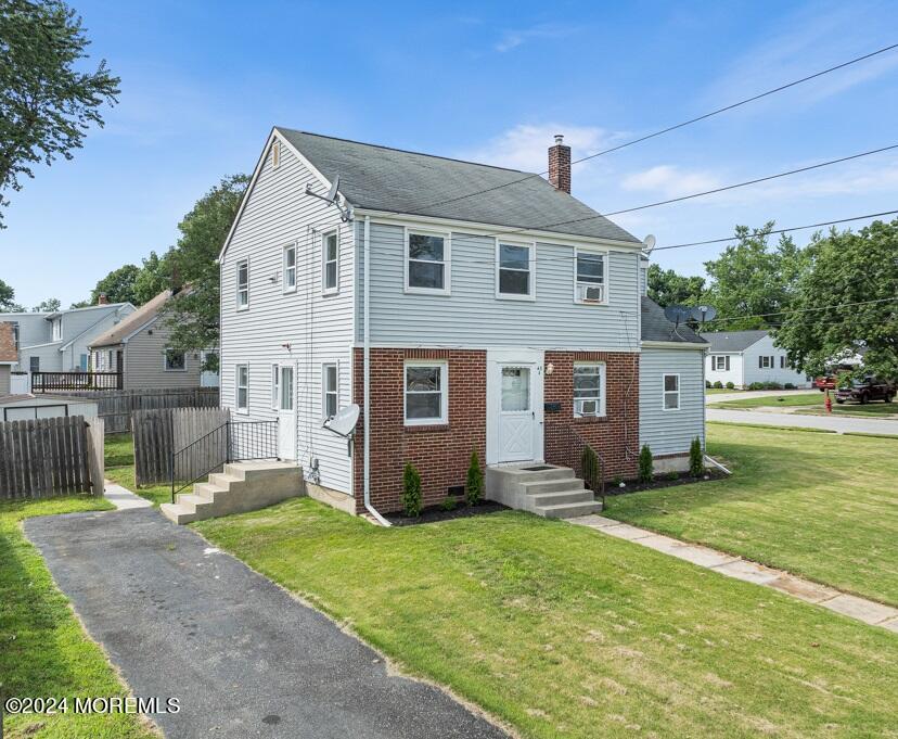 a front view of house with yard and trees in the background