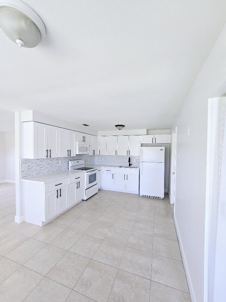 a large white kitchen with cabinets and a wooden floor