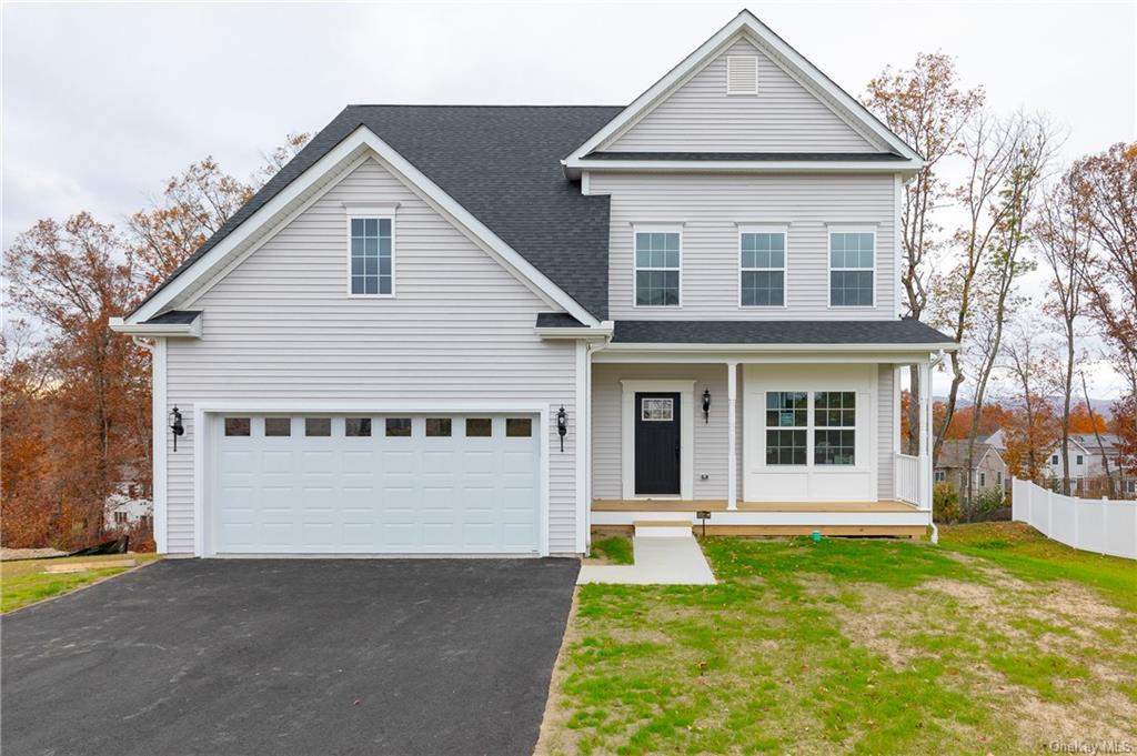 Front of property with covered porch, a garage, and a front lawn