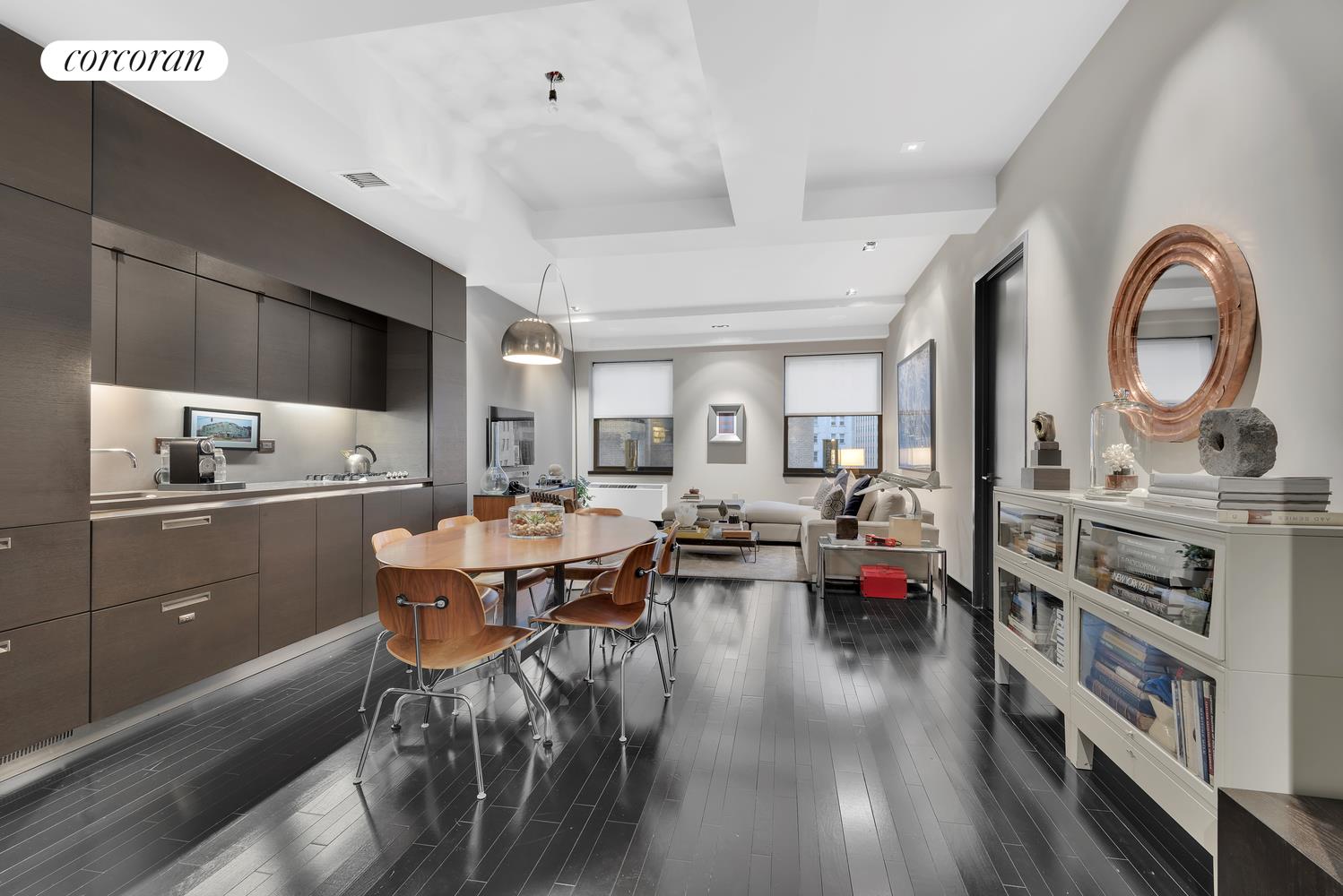 a living room with stainless steel appliances furniture a rug and a kitchen view