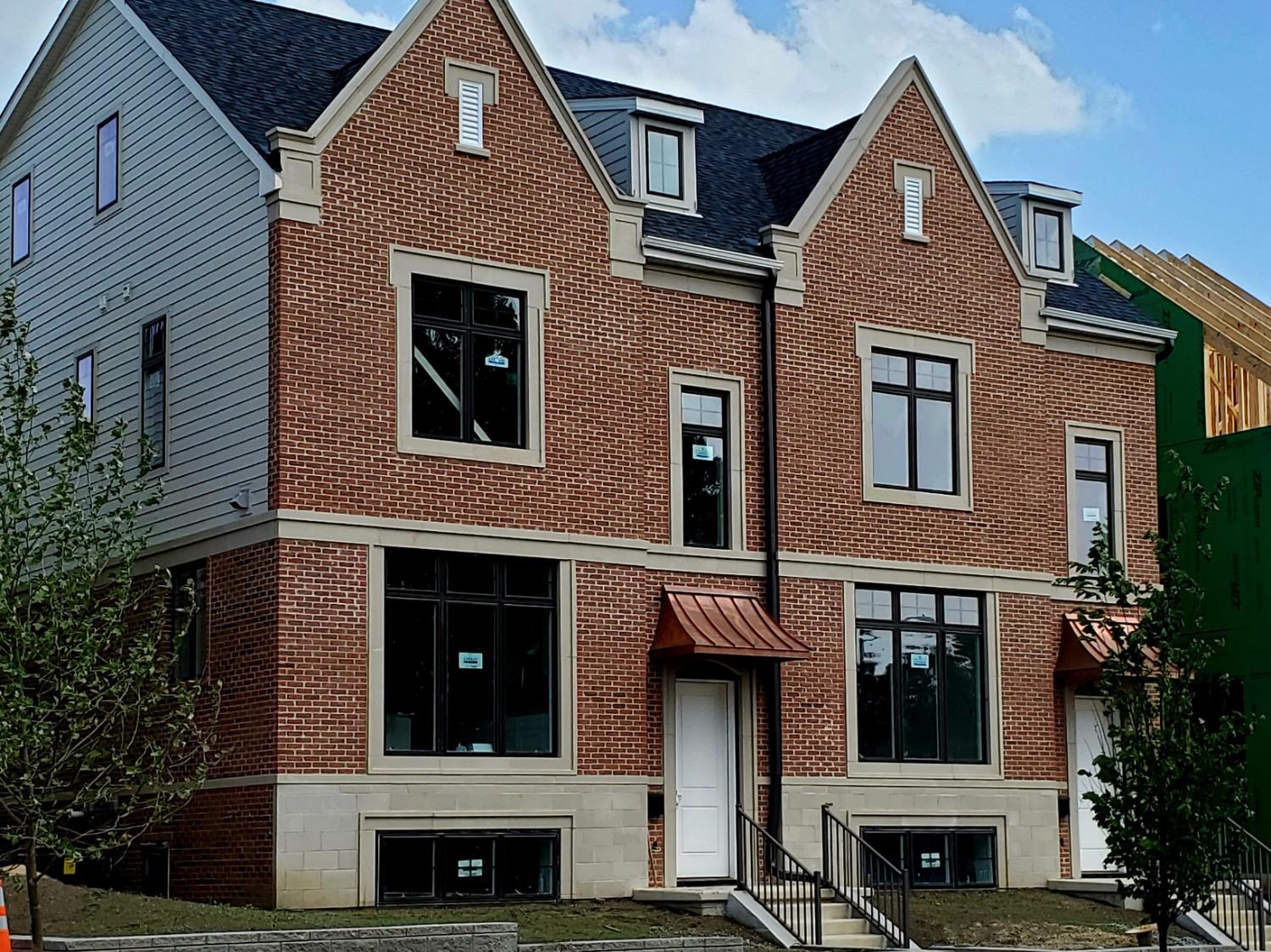 a view of a brick house with many windows and a tree