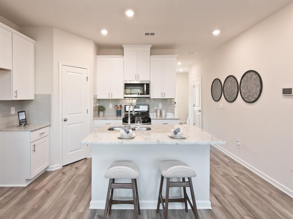 a kitchen with kitchen island granite countertop a sink cabinets and wooden floor